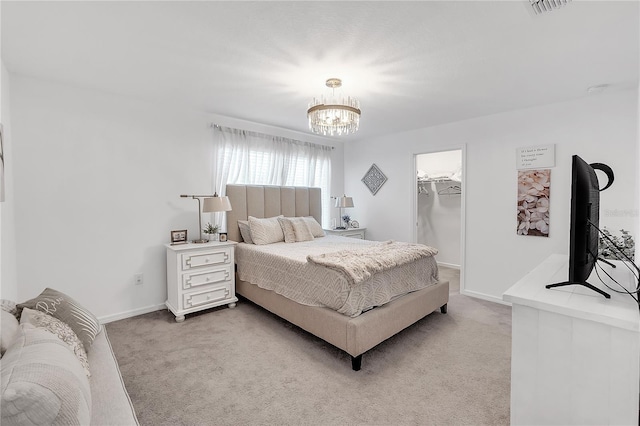 bedroom featuring light carpet, a spacious closet, baseboards, and an inviting chandelier