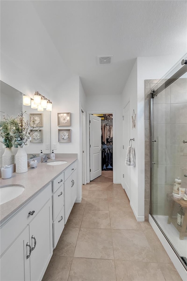 full bathroom featuring a walk in closet, visible vents, a sink, and a shower stall