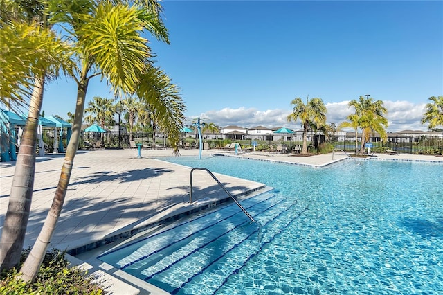 pool with a patio area and fence