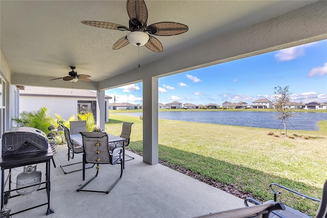 view of patio / terrace featuring a water view, ceiling fan, a residential view, and outdoor dining space