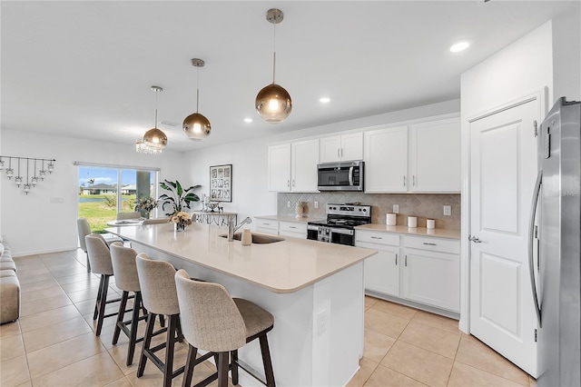 kitchen featuring light tile patterned floors, stainless steel appliances, a sink, white cabinetry, and tasteful backsplash