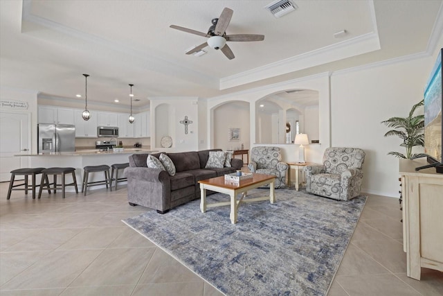 living room featuring arched walkways, a raised ceiling, visible vents, ornamental molding, and light tile patterned flooring