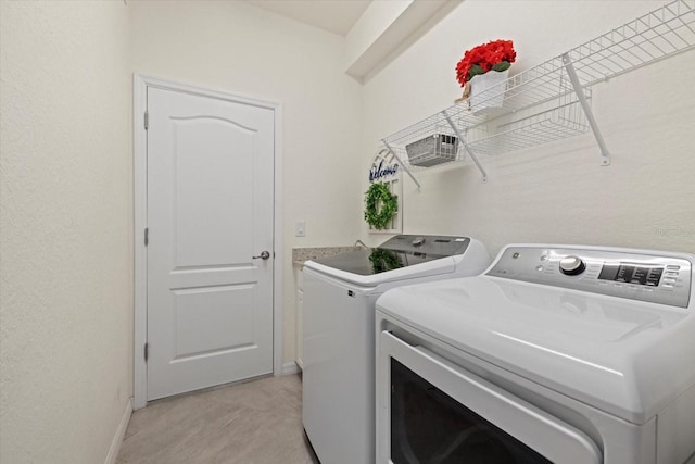 clothes washing area featuring laundry area, washing machine and dryer, and baseboards