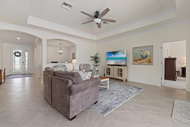 living area with arched walkways, a tray ceiling, light tile patterned floors, and visible vents