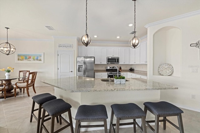 kitchen with stainless steel appliances, a sink, white cabinets, a large island, and decorative light fixtures