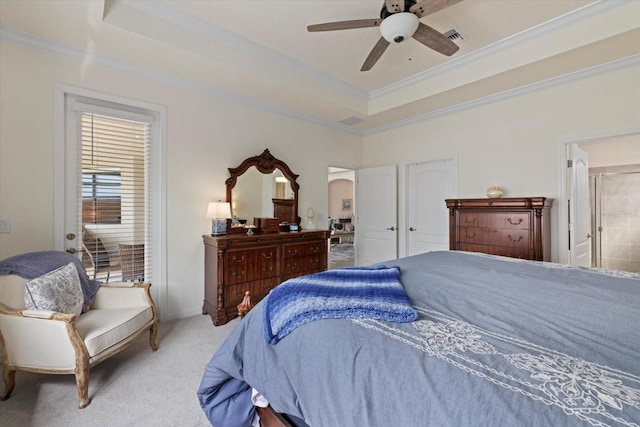 bedroom featuring a ceiling fan, light colored carpet, ornamental molding, ensuite bathroom, and a tray ceiling