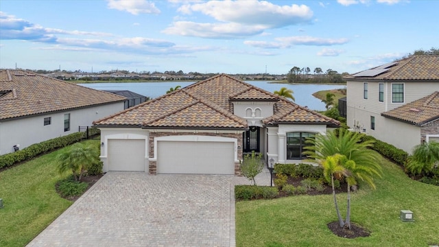 mediterranean / spanish home with a water view, a tile roof, and a garage