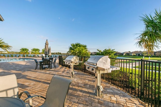 view of patio with outdoor dining area, a water view, a grill, and a community pool