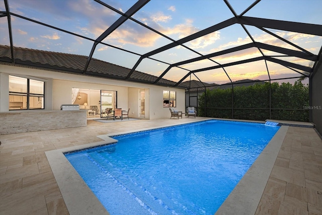 outdoor pool featuring glass enclosure and a patio area