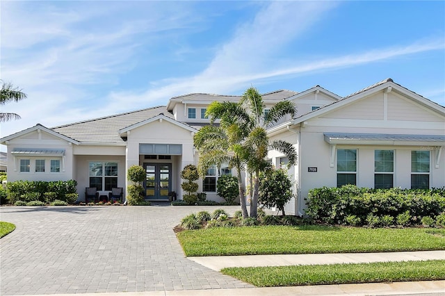 view of front of property with decorative driveway, a front yard, and stucco siding