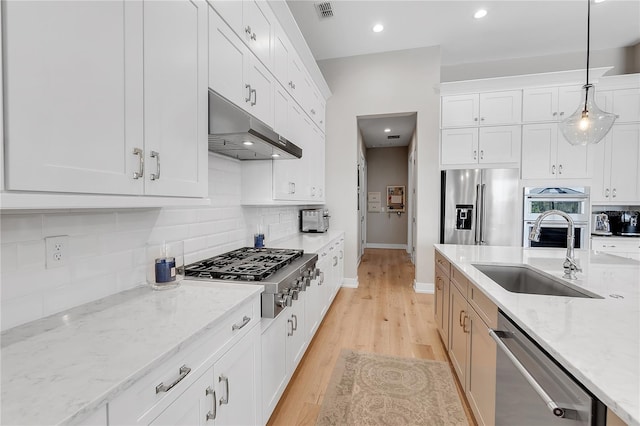 kitchen featuring visible vents, decorative backsplash, appliances with stainless steel finishes, under cabinet range hood, and a sink