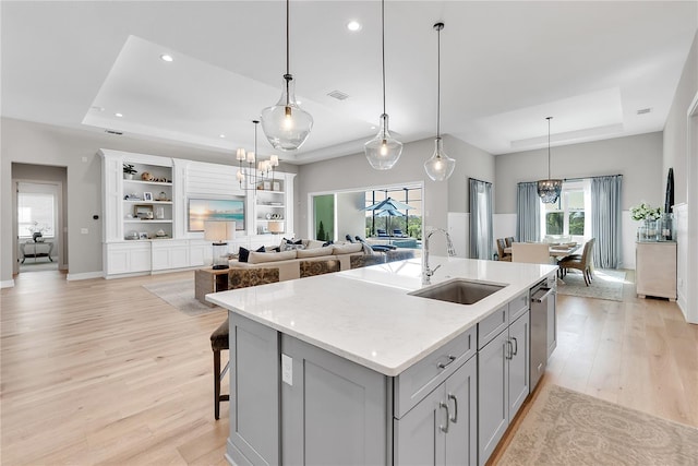 kitchen with dishwasher, visible vents, a tray ceiling, and a sink