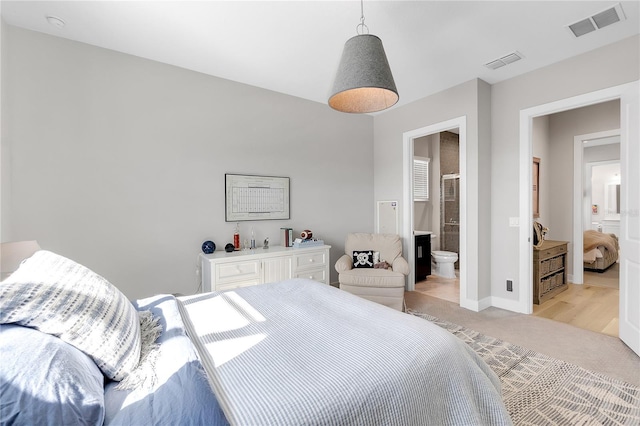 bedroom with connected bathroom, light colored carpet, visible vents, and baseboards