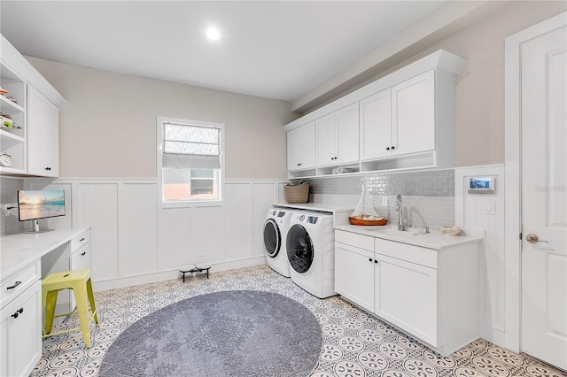 washroom with cabinet space, a wainscoted wall, a sink, and independent washer and dryer