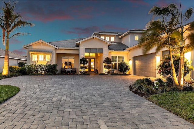 view of front of home featuring a garage, french doors, decorative driveway, and stucco siding