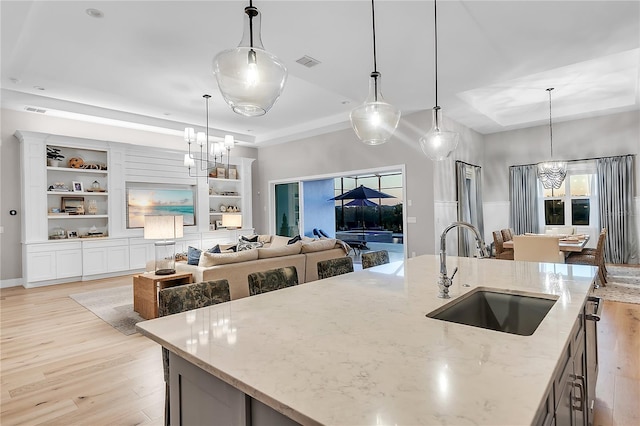 kitchen featuring a chandelier, a tray ceiling, a sink, and visible vents