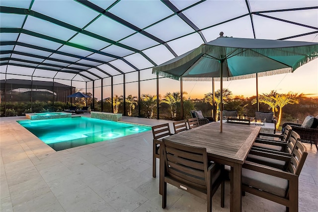 pool at dusk with a patio, a pool with connected hot tub, and glass enclosure