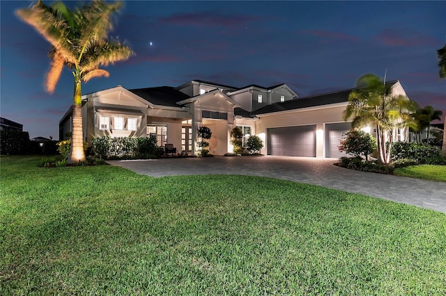 view of front of house with a garage, a front lawn, decorative driveway, and stucco siding