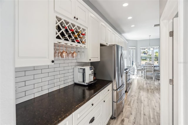 kitchen featuring white cabinets, light wood-style floors, tasteful backsplash, and freestanding refrigerator