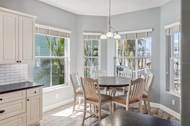 dining room with a chandelier, plenty of natural light, light wood finished floors, and baseboards