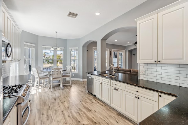 kitchen featuring visible vents, arched walkways, a sink, appliances with stainless steel finishes, and backsplash