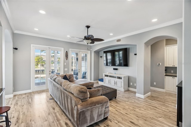 living room with light wood-style flooring, a ceiling fan, french doors, arched walkways, and baseboards