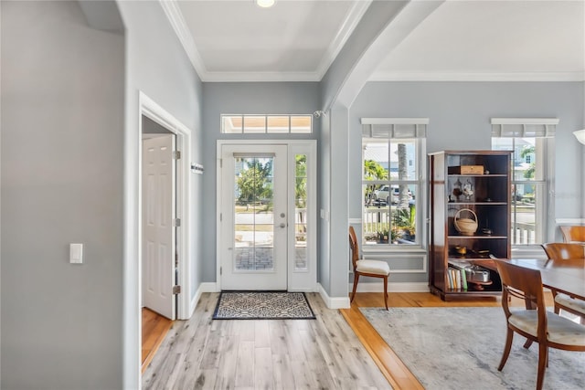 foyer entrance featuring a wealth of natural light, arched walkways, ornamental molding, and wood finished floors