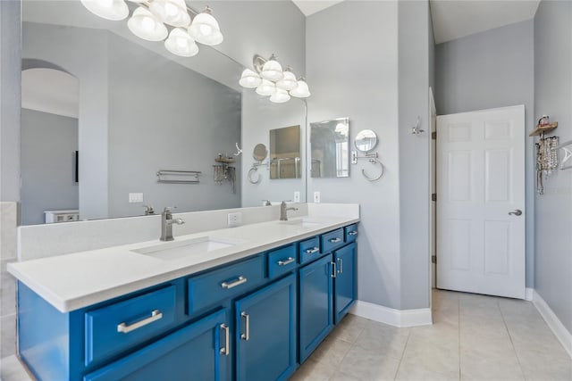 bathroom with tile patterned flooring, double vanity, baseboards, and a sink