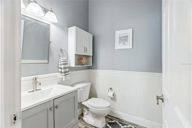 bathroom featuring vanity, toilet, and wainscoting