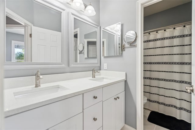 bathroom featuring double vanity, toilet, and a sink