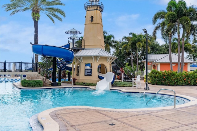 community pool with stairs, a patio, and a water slide