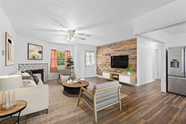 living room featuring dark wood-style floors, a textured ceiling, a fireplace, and visible vents