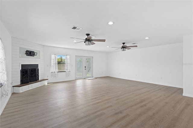 unfurnished living room featuring recessed lighting, a large fireplace, wood finished floors, visible vents, and french doors