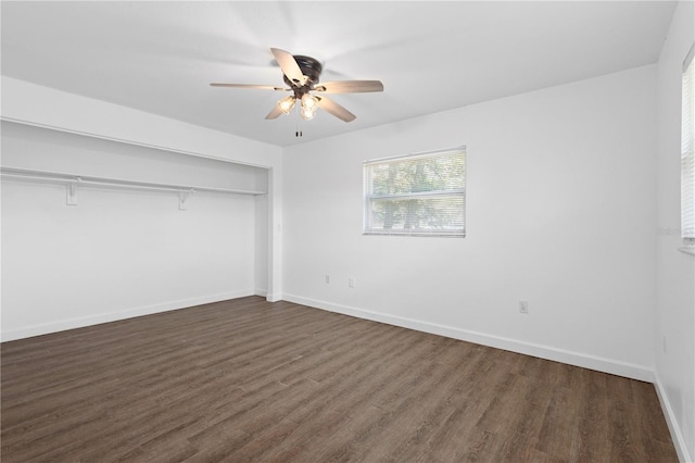 unfurnished bedroom featuring dark wood-type flooring, a closet, ceiling fan, and baseboards