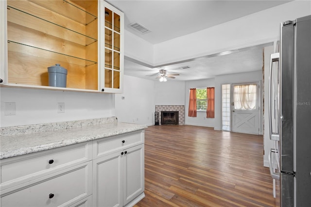 kitchen featuring ceiling fan, a fireplace, visible vents, freestanding refrigerator, and dark wood finished floors