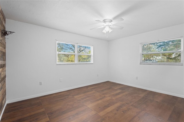 empty room with wood finished floors, a ceiling fan, and baseboards