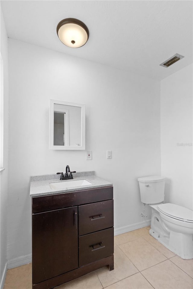 bathroom featuring baseboards, visible vents, toilet, tile patterned floors, and vanity