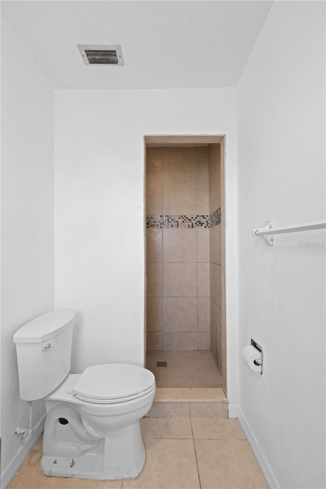 bathroom featuring toilet, visible vents, baseboards, a shower stall, and tile patterned floors