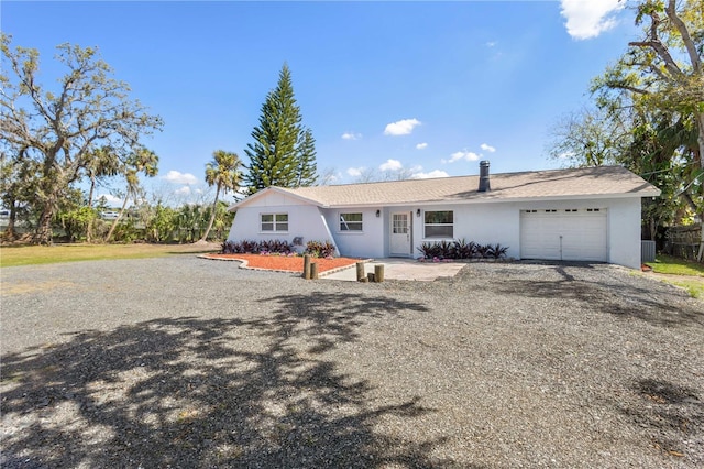 ranch-style house featuring a garage, driveway, and stucco siding