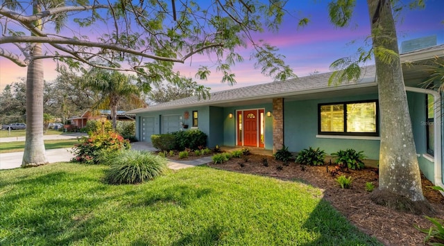 ranch-style home with a yard, an attached garage, and stucco siding