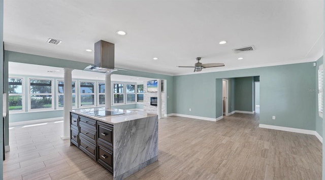 kitchen with black electric stovetop, ceiling fan, visible vents, and a stone fireplace