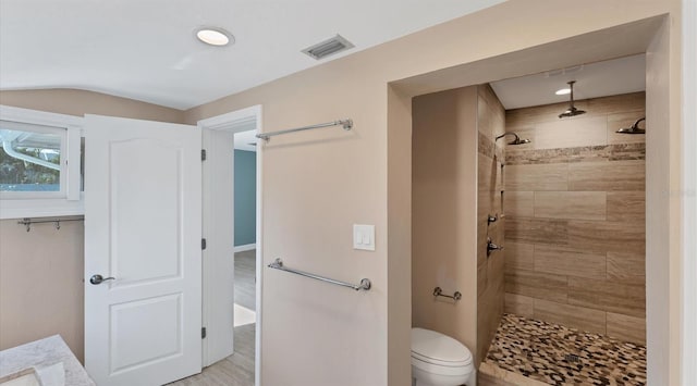 bathroom featuring toilet, visible vents, vaulted ceiling, and tiled shower