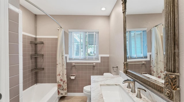 bathroom featuring shower / tub combo with curtain, tile walls, toilet, wainscoting, and vanity