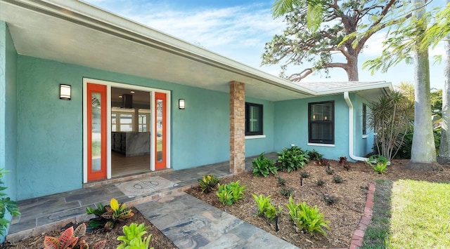 doorway to property featuring a porch and stucco siding