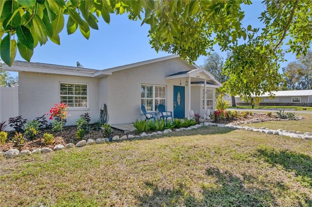 view of front of property with fence, a front lawn, and stucco siding