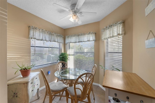 dining room with a textured ceiling, light tile patterned floors, a ceiling fan, and baseboards