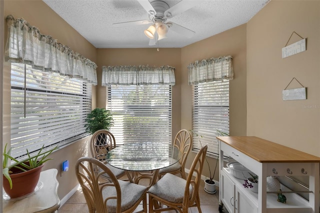 dining area featuring a textured ceiling, light tile patterned floors, a ceiling fan, and baseboards