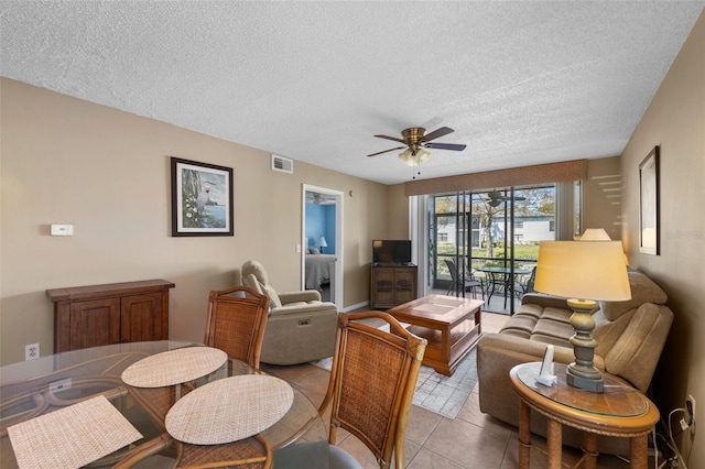 living area featuring a textured ceiling, visible vents, a ceiling fan, and light tile patterned flooring