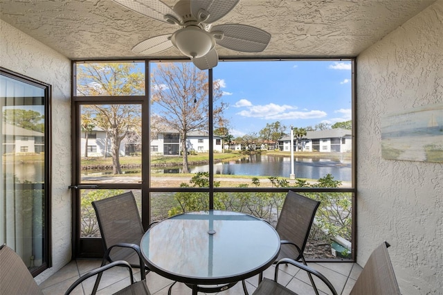 sunroom featuring a residential view, a water view, and ceiling fan