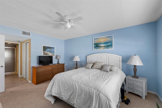 carpeted bedroom with ceiling fan, a textured ceiling, visible vents, and baseboards